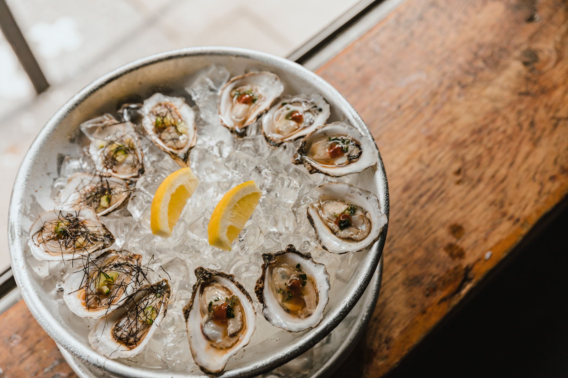A dozen oysters on the half shell arranged on crushed ice with lemon wedges