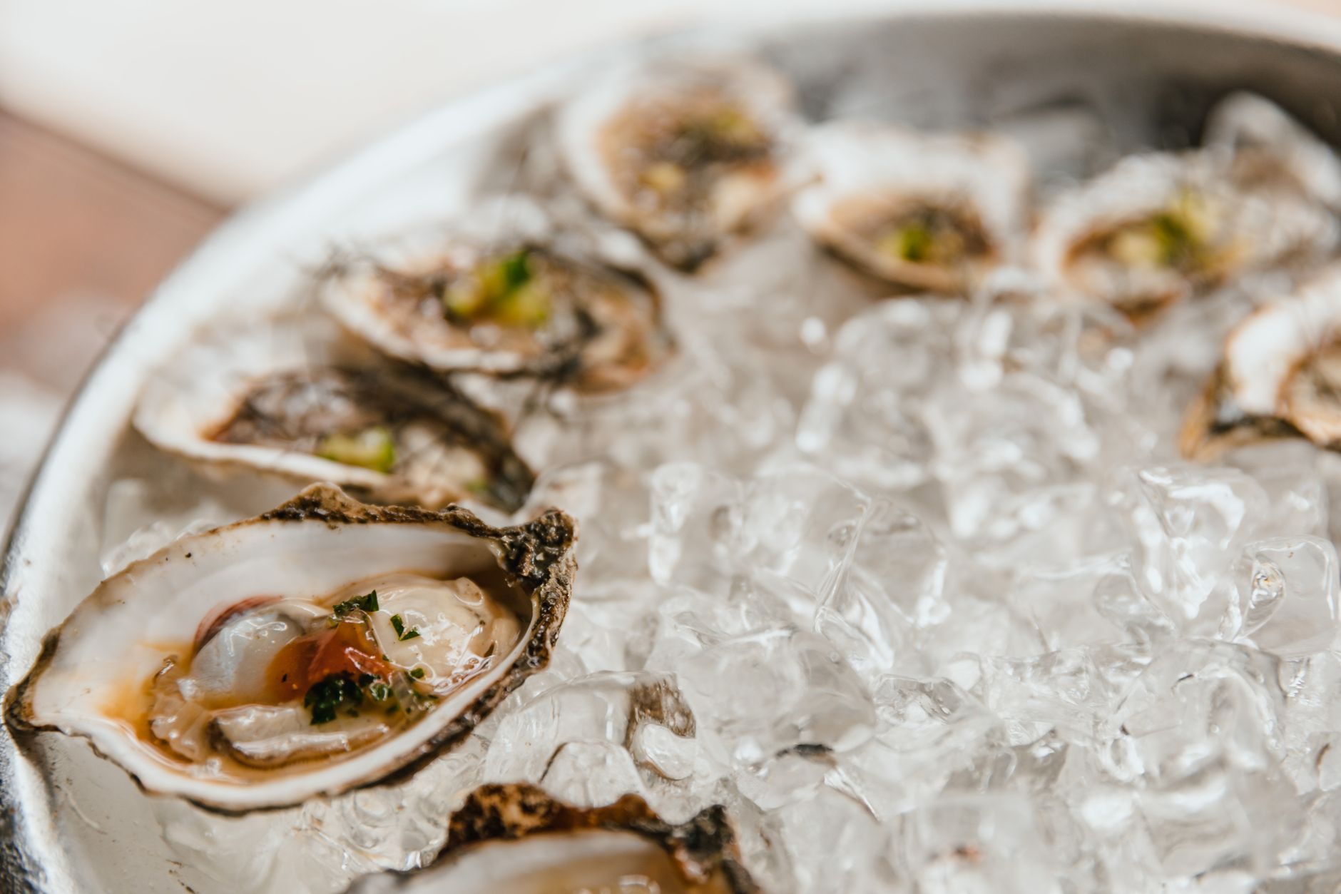 A raw bar station with crushed ice, shellfish on platters, and shucking tools